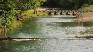 A river with people standing on the banks and a bridge in the background.