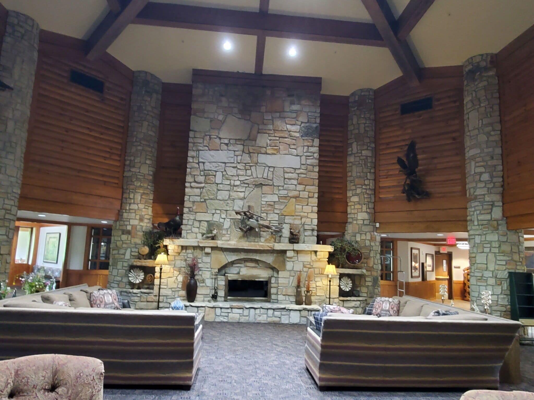 A spacious lobby with a stone fireplace, wooden beams, and comfortable seating areas.