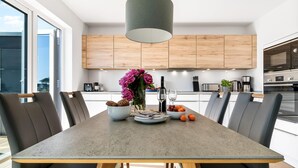 A modern kitchen with a dining table, chairs, and a pendant light.