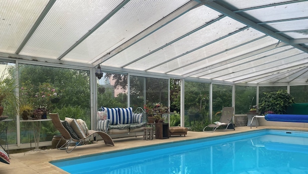 Ein überdachter Pool mit Liegestühlen und Blumentöpfen.