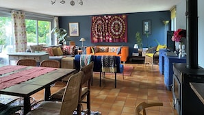 Ein gemütliches Wohnzimmer mit Essbereich, einem blauen Sofa, einem gemusterten Teppich und einem großen Wandteppich.