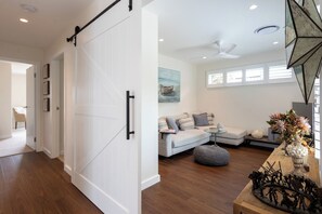 Un interior moderno con una puerta corredera estilo granero, un sofá modular, una mesa de comedor con un florero y un ventilador de techo.