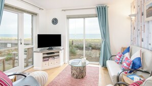 A living room with a TV, seating, a coffee table, and a view of the sea. - 2 bedroom accommodation in Seahouses (Seahouses)