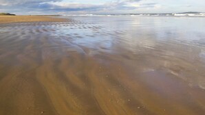 A beach with wet sand and a cloudy sky. - 2 bedroom accommodation in Seahouses (Seahouses)