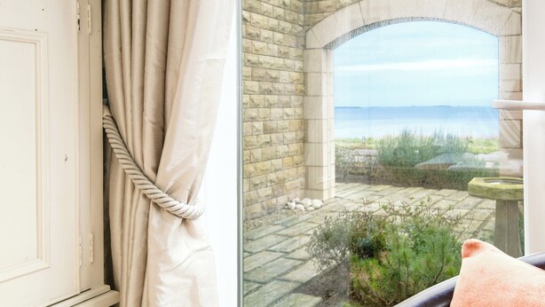 A room with a view of a stone patio and a body of water. - 2 bedroom accommodation in Seahouses (Seahouses)