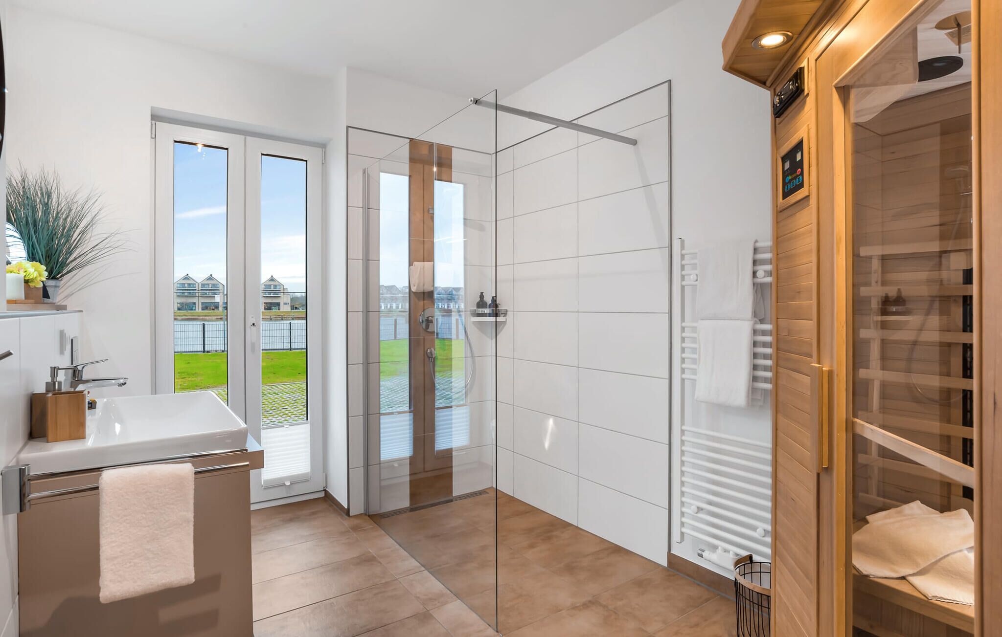 Un baño moderno con cabina de ducha de vidrio, bañera y vista al agua.