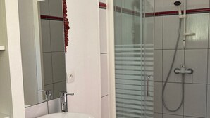 Ein Badezimmer mit Waschbecken, Spiegel und Duschkabine aus Glas.
