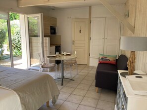 Et værelse med en seng, et bord dækket til to personer, en sofa og en lampe.