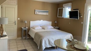 Ein Schlafzimmer mit Bett, Nachttischen, Fernseher und Esstisch mit Stühlen.