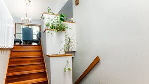 Una escalera de madera con una pared blanca y una estantería con plantas.