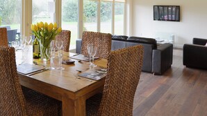 A dining area with a wooden table, woven chairs, and a vase of yellow flowers.