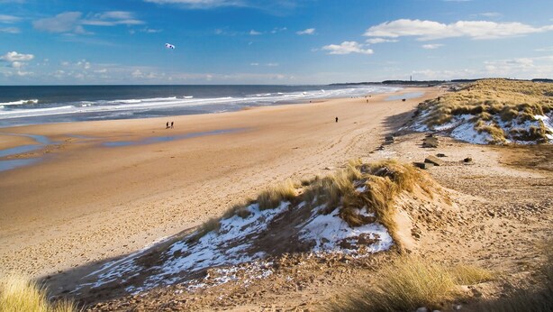 A beach with sand dunes and a clear sky.