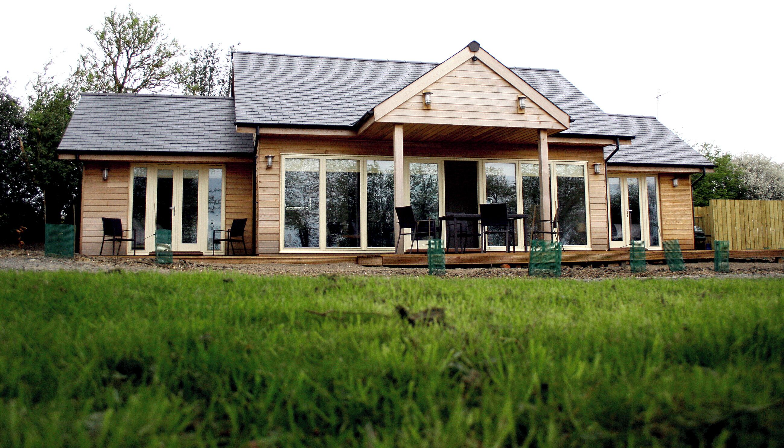 A two-story house with a large deck, sliding glass doors, and a covered patio area.