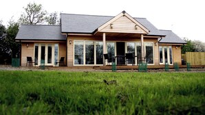 A two-story house with a large deck, sliding glass doors, and a covered patio area.