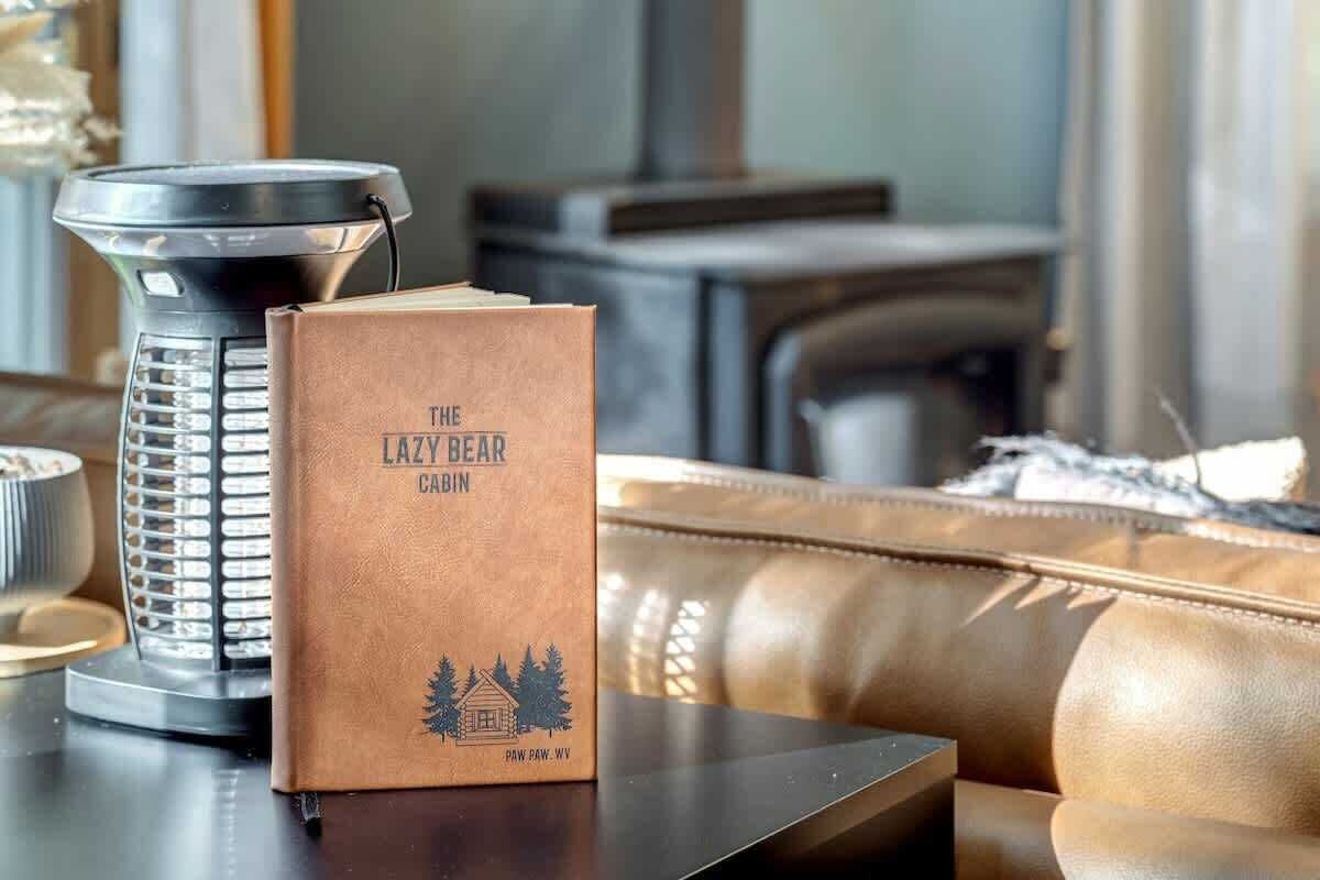 A book titled 'The Lazy Bear Cabin' on a table next to a black kettle.