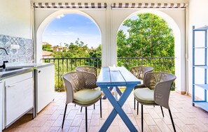 Enjoy a serene view of the lush landscape from this balcony, featuring a table, chairs, sink, and bench.