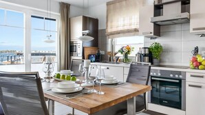 Une cuisine moderne avec un coin repas, dotée d’appareils électroménagers en acier inoxydable, offrant une vue sur la mer et aménagée pour le petit-déjeuner.