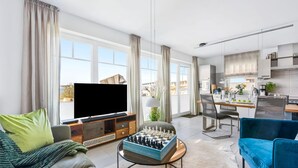 Un salon moderne avec un téléviseur à écran plat, un jeu d’échecs et un canapé.