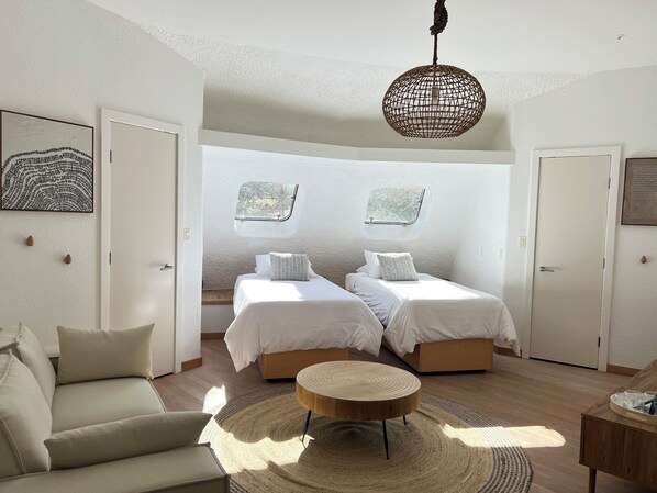 A modern bedroom with two beds, a round wooden coffee table, and a hanging light fixture. - The Uzu Dome, Sedona architectural master piece on the vortex (Sedona)