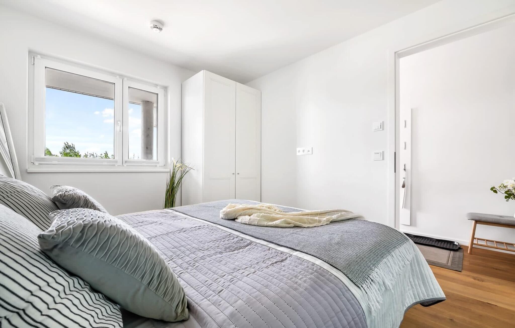 A bedroom with a large bed, a window, and white walls.
