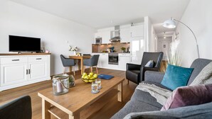 A modern living room with a wooden coffee table, a grey sofa, and a TV on a wooden stand. - Cozy apartment in Olpenitz (Olpenitz)