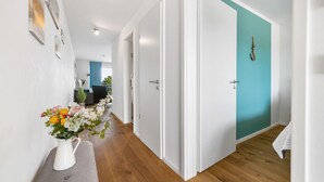 A hallway with white walls, a teal door, and a white vase with flowers. - Cozy apartment in Olpenitz (Olpenitz)