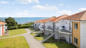 Un hotel a la costa amb diversos balcons, un camí cap a l'entrada i vista al mar.