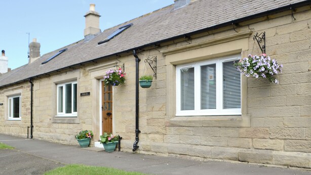 A row of stone houses with pitched roofs, a central door, and flower baskets. - Lovely property with an open staircase leading to 2 bedrooms and a bathroom. (Ellington, near Druridge)