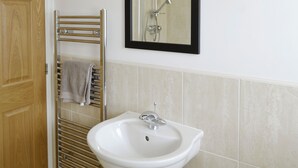 Een badkamer met een wit wastafelmeubel, een handdoekhouder en een spiegel.
