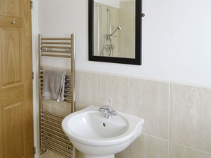 Une salle de bain avec un lavabo blanc, un porte-serviettes et un miroir.
