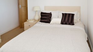 A neatly made bed with a patterned bedspread, two pillows, a bedside lamp, and a wooden door. - Lovely property with an open staircase leading to 2 bedrooms and a bathroom. (Ellington, near Druridge)