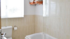 Een badkamer met toilet, wastafel en bad.
