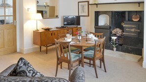 A dining area with a wooden table set for four, a sofa, a cabinet, and a fireplace. - Lovely property with an open staircase leading to 2 bedrooms and a bathroom. (Ellington, near Druridge)