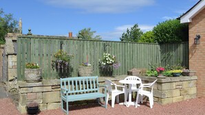 A patio with a bench and chairs, surrounded by stone walls and a wooden fence. - Lovely property with an open staircase leading to 2 bedrooms and a bathroom. (Ellington, near Druridge)