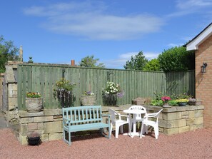 A patio with a bench and chairs, surrounded by stone walls and a wooden fence. - Lovely property with an open staircase leading to 2 bedrooms and a bathroom. (Ellington, near Druridge)