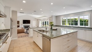 A spacious kitchen with a large island, white cabinetry, and a view of the outdoors through large windows. - Large Quiet Sonoma Oasis with Pool (Sonoma)