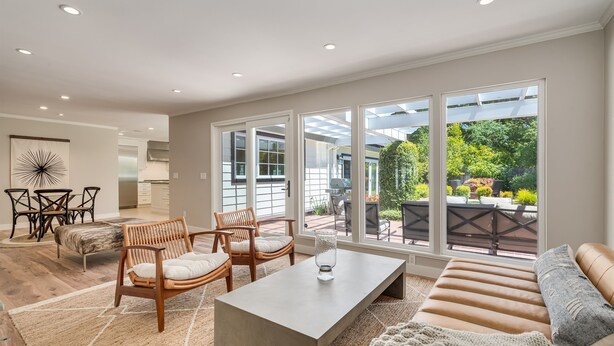A spacious living room with a large window, a dining area, and a kitchen in the background. - Large Quiet Sonoma Oasis with Pool (Sonoma)