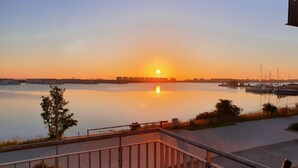 Blick auf das Wasser bei Sonnenuntergang, ruhige Gewässer und eine Anlegestelle mit Booten.