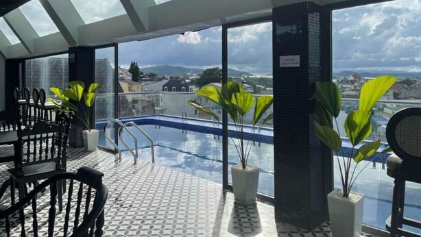 Ein Poolbereich auf dem Dach mit Blick auf die Stadt, Kübelpflanzen und Sitzmöglichkeiten im Freien.