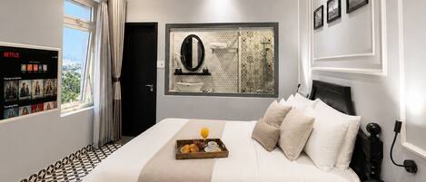 A hotel room with a bed, bedside table, and a wall-mounted TV displaying Netflix content.