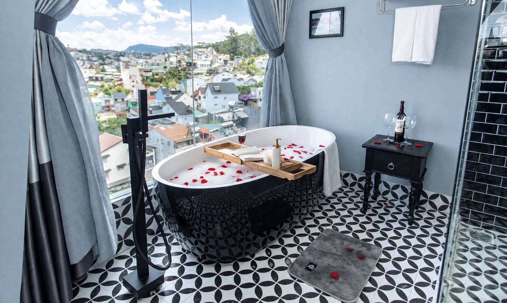 Un bagno con una vasca, un tavolino con articoli da toilette, un portasciugamani e vista sulla città.