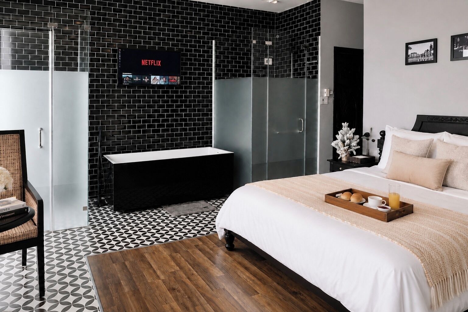 Une chambre moderne avec un mur en briques noires, un écran pour regarder Netflix, un lit avec un plateau de petit-déjeuner et une armoire.