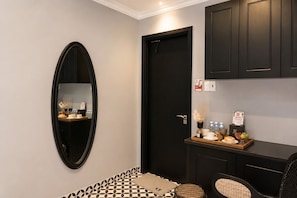 A hotel room with a black door, a mirror, a small table with a tray of items, and a patterned floor. - TTR Skypool View Hotel (Cam Ly - Da Lat)