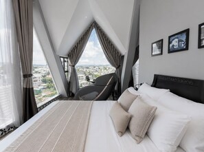 A modern hotel room with a large bed, a chair, and a city view. - TTR Skypool View Hotel (Cam Ly - Da Lat)