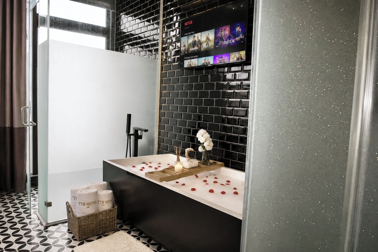 Un bagno moderno con una parete rivestita in piastrelle nere, una vasca da bagno bianca e un'area doccia.