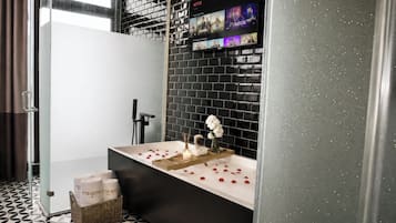 Un bagno moderno con una parete rivestita in piastrelle nere, una vasca da bagno bianca e un'area doccia.