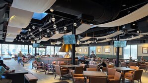En rummelig restaurant med højt til loftet, lysekroner og en bar.