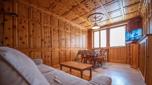 A wooden cabin interior with a sofa, a dining table, and a TV in the background. - Be won over by the Valente two-room apartment and enjoy your vacation (Livigno)