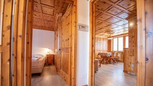 A wooden interior with a bed, a dining area, and a kitchen. - Be won over by the Valente two-room apartment and enjoy your vacation (Livigno)