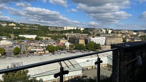 Un paysage urbain mêlant des immeubles résidentiels et commerciaux, un parking et un ciel dégagé parsemé de nuages.